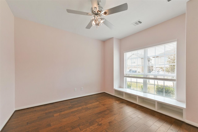 unfurnished room with ceiling fan, baseboards, visible vents, and dark wood finished floors