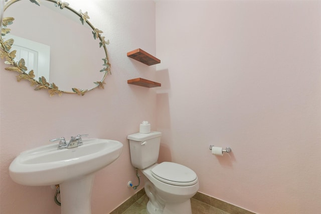 half bathroom with baseboards, toilet, and tile patterned floors