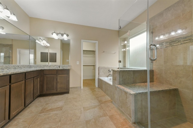 bathroom with tile patterned flooring, vanity, a bath, a stall shower, and a walk in closet