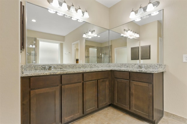 full bath featuring double vanity, a stall shower, a sink, and tile patterned floors