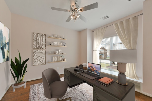 home office featuring a ceiling fan, visible vents, baseboards, and wood finished floors