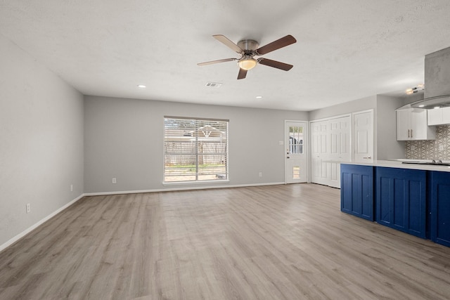 unfurnished living room with light wood finished floors, visible vents, ceiling fan, a textured ceiling, and baseboards