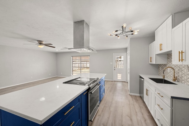 kitchen with appliances with stainless steel finishes, ventilation hood, blue cabinetry, white cabinetry, and a sink