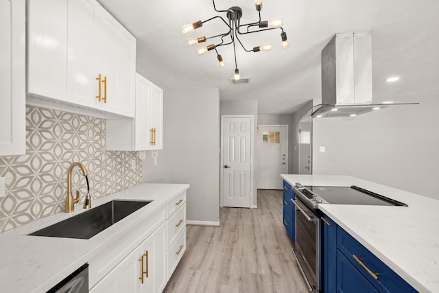 kitchen featuring island range hood, a sink, white cabinets, appliances with stainless steel finishes, and blue cabinetry