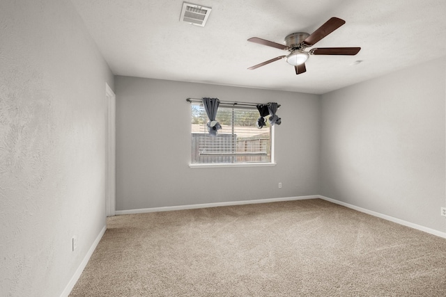 carpeted empty room with visible vents, ceiling fan, a textured ceiling, and baseboards