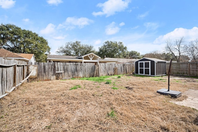 view of yard featuring a storage shed, a fenced backyard, and an outbuilding