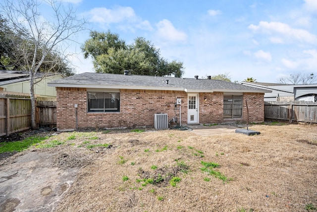 rear view of property featuring cooling unit, a fenced backyard, and brick siding