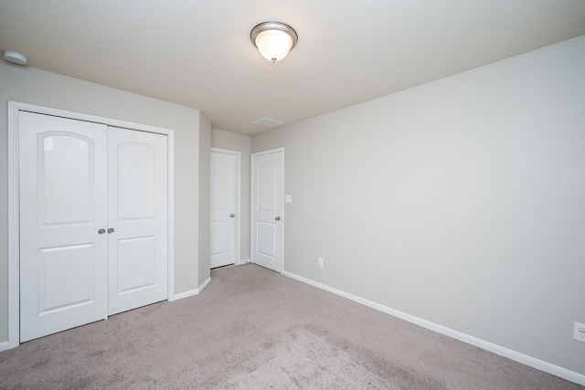 unfurnished bedroom featuring visible vents, baseboards, a closet, and light colored carpet
