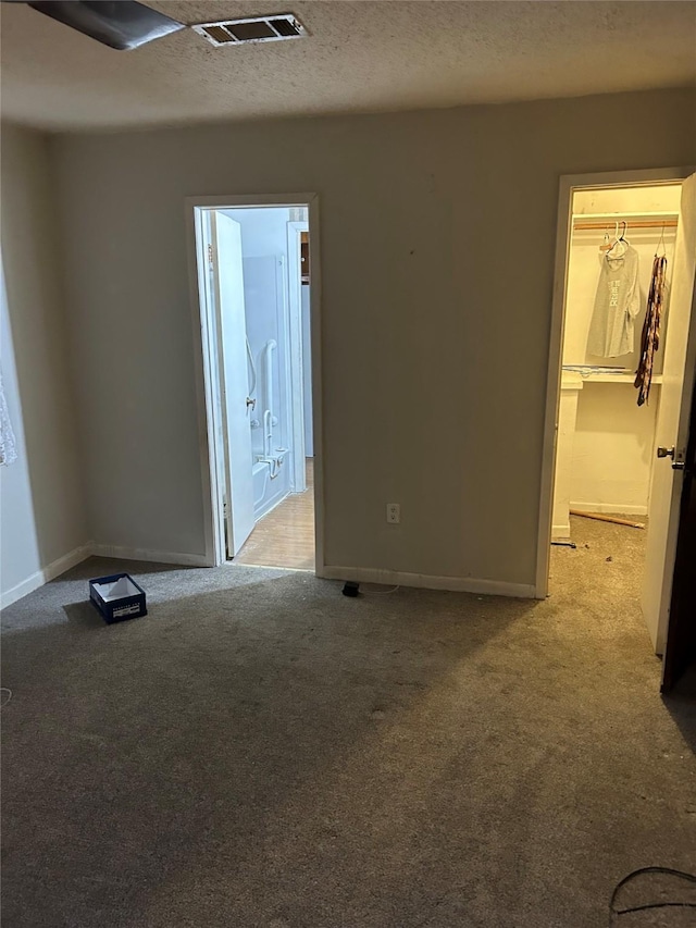 carpeted spare room with a textured ceiling, visible vents, and baseboards