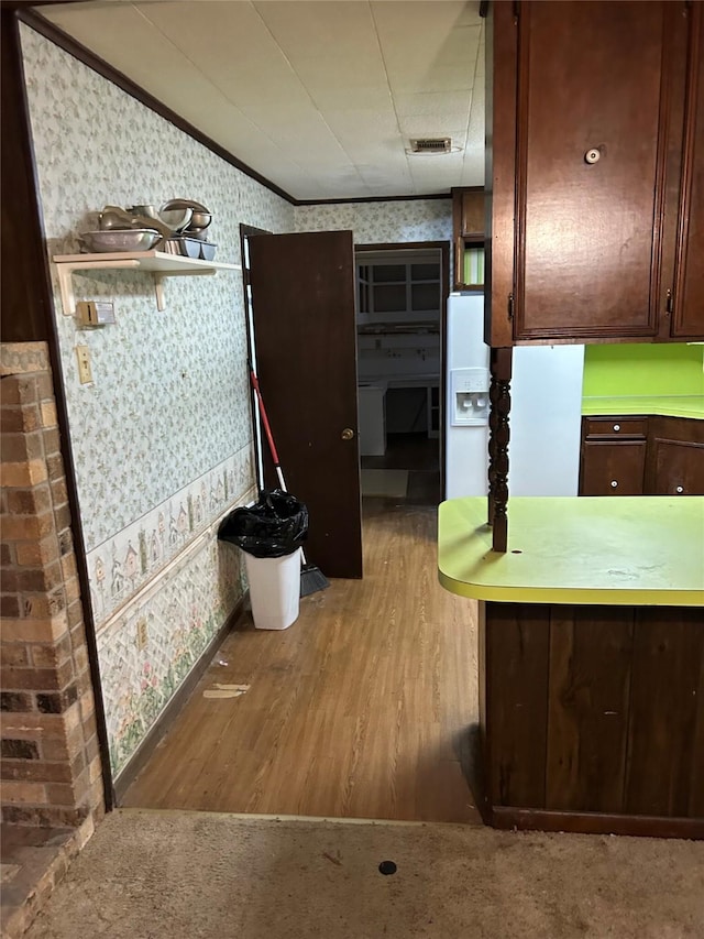 kitchen featuring ornamental molding, light countertops, visible vents, and wallpapered walls