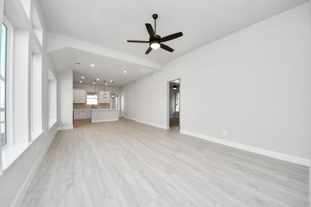 21311 Bridle Rose Trl, Tomball, TX 77377 - unfurnished living room featuring light wood-style flooring, a ceiling fan, recessed lighting, a sink, and baseboards
