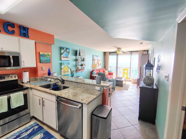 kitchen featuring stainless steel appliances, a peninsula, a sink, white cabinetry, and open floor plan