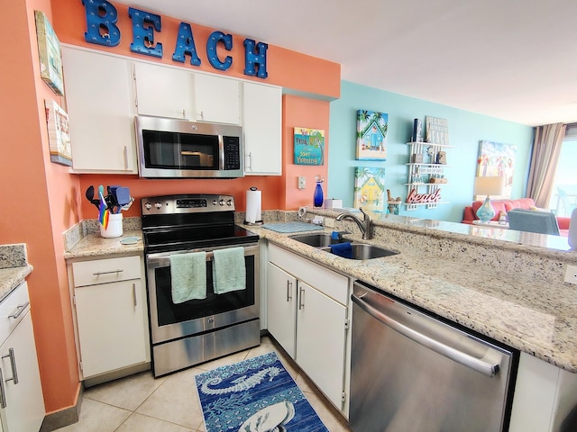 kitchen featuring stainless steel appliances, light stone counters, a sink, and white cabinetry