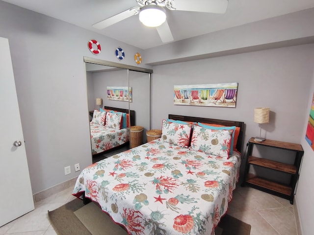 bedroom with light tile patterned floors, baseboards, a ceiling fan, and a closet