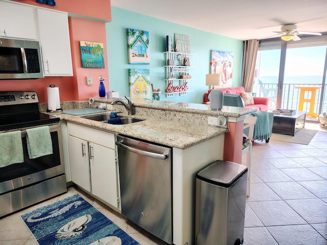 kitchen with stainless steel appliances, a peninsula, a sink, and white cabinets