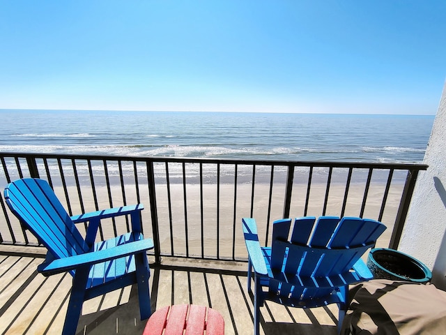 balcony with a water view and a view of the beach