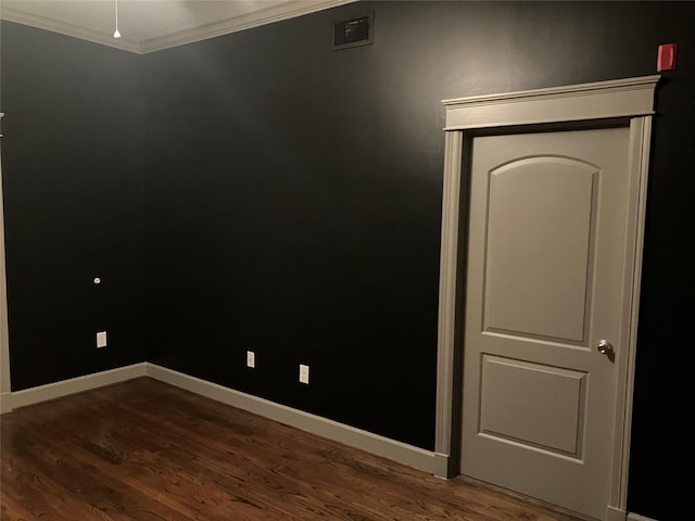 unfurnished room featuring dark wood-type flooring, visible vents, crown molding, and baseboards