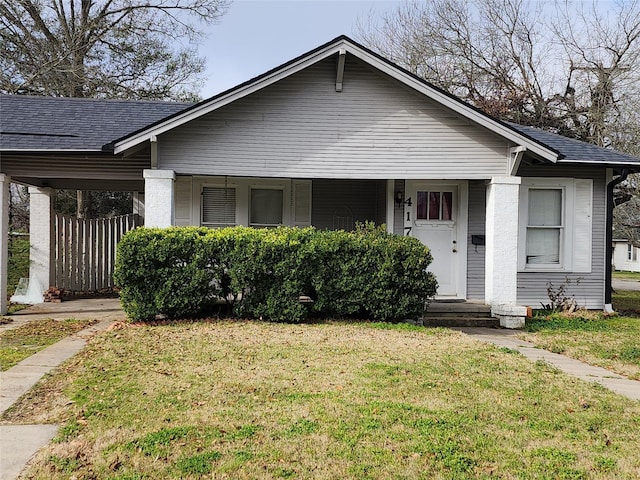 bungalow-style house featuring roof with shingles and a front yard