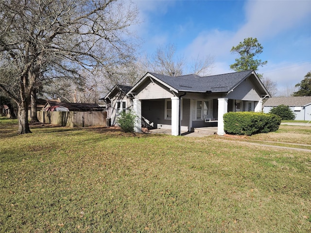 view of front of property featuring a patio area, a front lawn, and a shingled roof