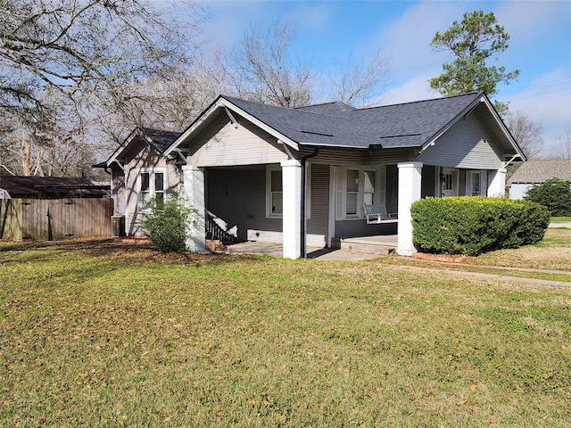 bungalow with a porch, a front yard, fence, and a shingled roof