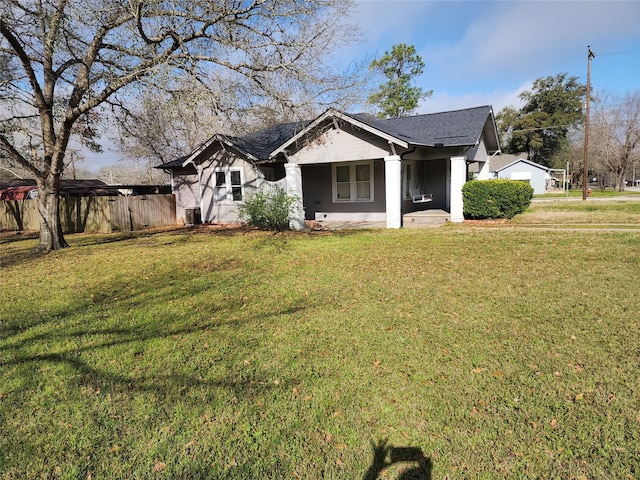 bungalow-style house featuring a shingled roof, fence, and a front yard