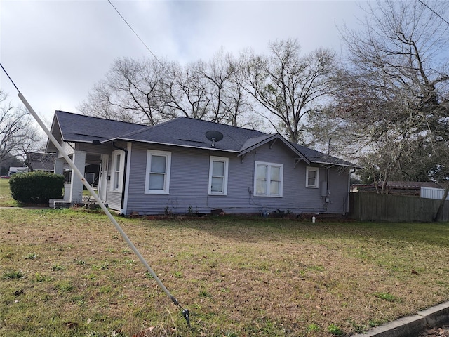 rear view of house featuring a yard and fence