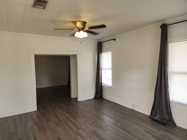 empty room featuring baseboards, visible vents, and dark wood finished floors