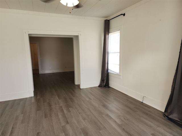 unfurnished room with dark wood-style floors, ceiling fan, baseboards, and crown molding