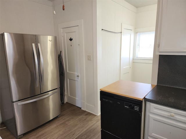 kitchen featuring black dishwasher, white cabinets, dark countertops, wood finished floors, and freestanding refrigerator