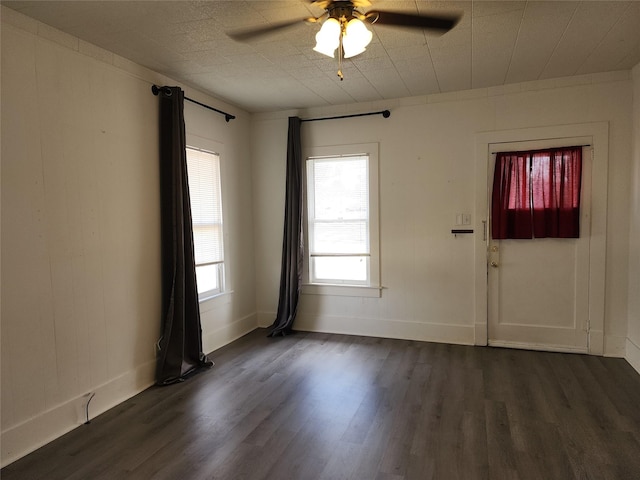 interior space with baseboards, a ceiling fan, and dark wood-style flooring