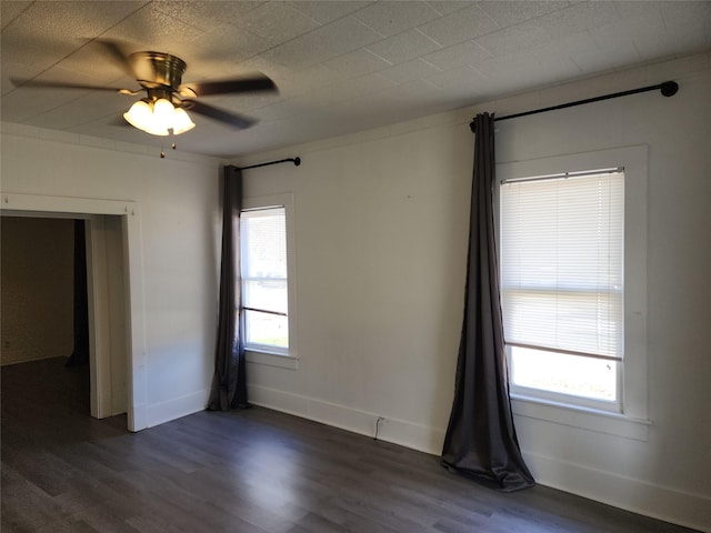 empty room with dark wood-style flooring, plenty of natural light, and baseboards