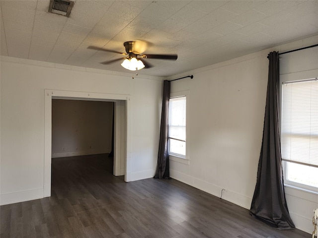 unfurnished room featuring visible vents, dark wood finished floors, baseboards, and ceiling fan