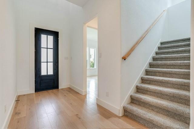 entryway featuring stairs, light wood-style flooring, baseboards, and a healthy amount of sunlight