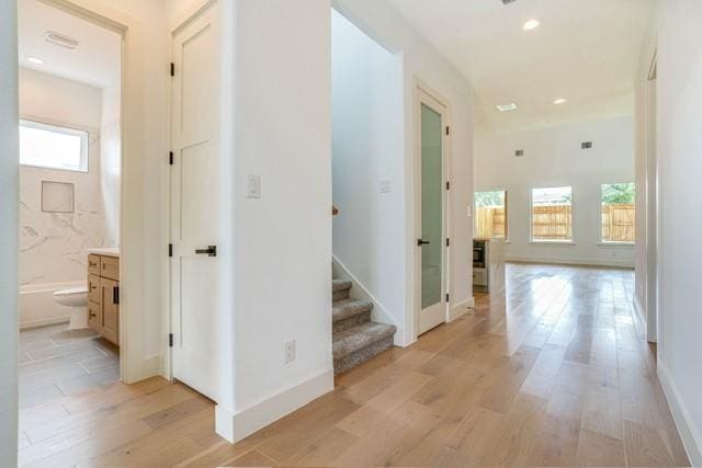 hall with light wood-style flooring, recessed lighting, baseboards, and stairs