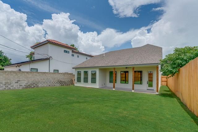 rear view of house with a fenced backyard and a lawn