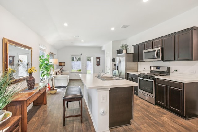 kitchen with a sink, open floor plan, light countertops, appliances with stainless steel finishes, and a center island with sink