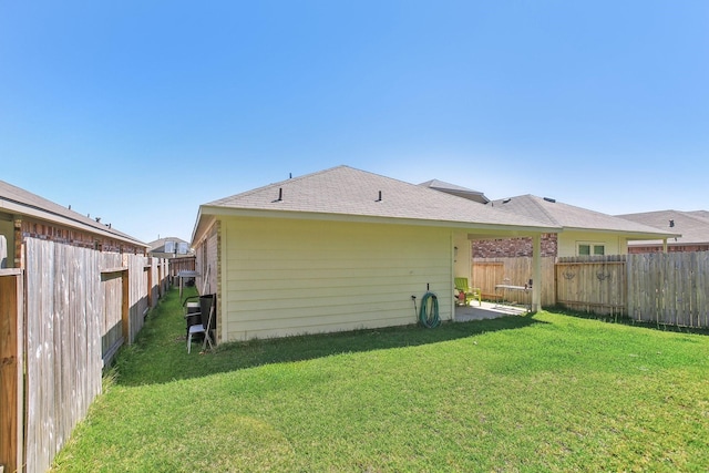 back of house with a fenced backyard and a yard