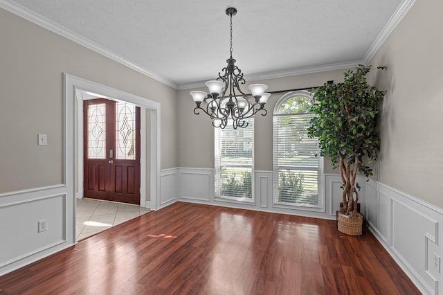 foyer entrance featuring a decorative wall, wood finished floors, and crown molding