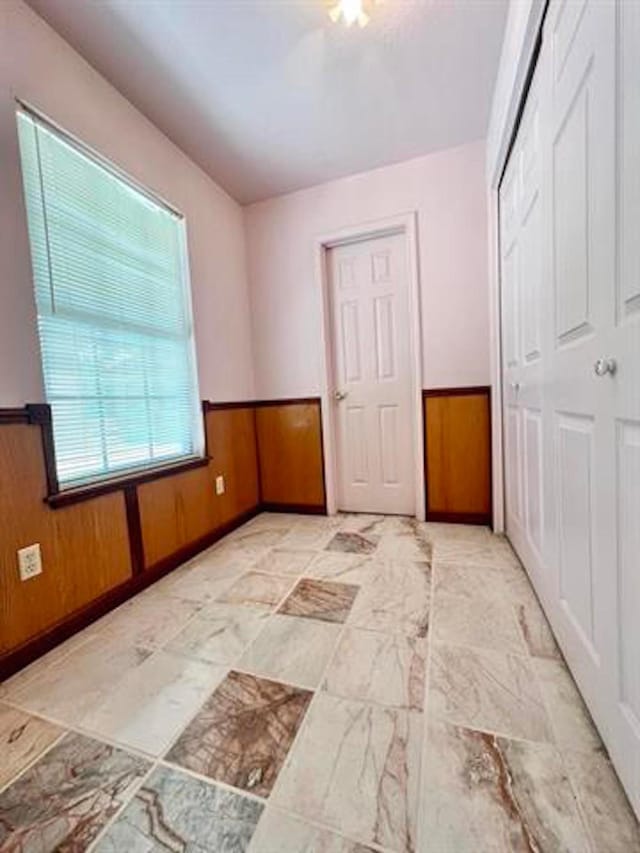 unfurnished bedroom with a closet, a wainscoted wall, and wood walls