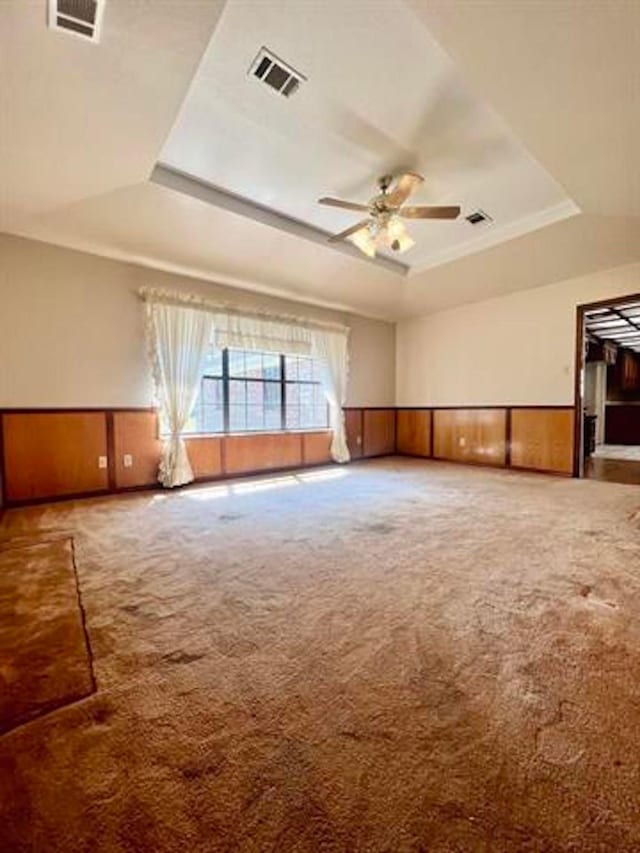 unfurnished room featuring a raised ceiling, visible vents, and a wainscoted wall