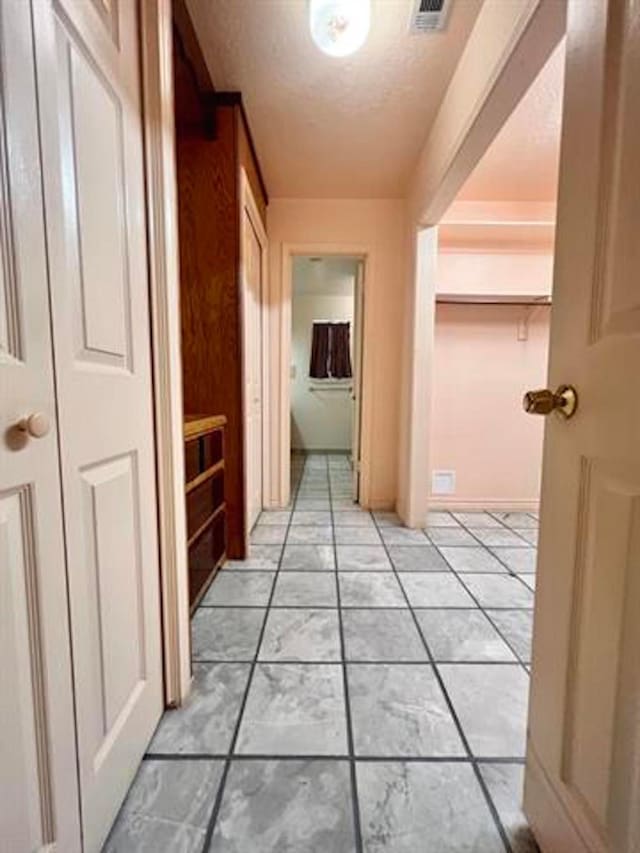 hall with visible vents and a textured ceiling