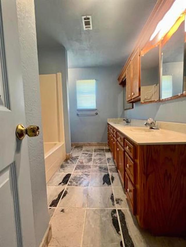 full bath with visible vents, vanity, and baseboards