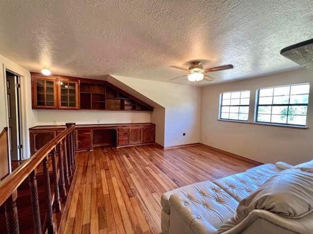 bonus room featuring a ceiling fan, a textured ceiling, and wood finished floors