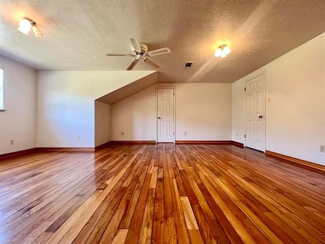 bonus room featuring light wood-style floors, ceiling fan, baseboards, and a textured ceiling