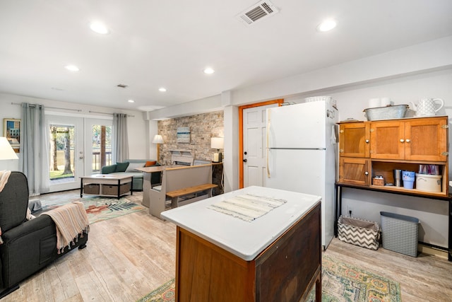 kitchen featuring light wood-type flooring, freestanding refrigerator, open floor plan, and visible vents