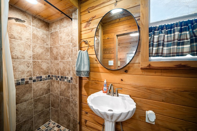 bathroom with a sink, wood walls, and a shower stall