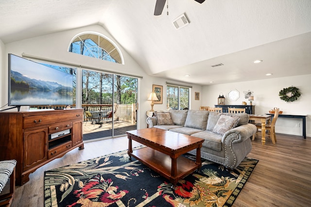 living room featuring visible vents, light wood-style floors, a ceiling fan, vaulted ceiling, and a textured ceiling