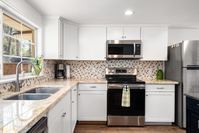 kitchen with stainless steel appliances, white cabinets, a sink, and tasteful backsplash