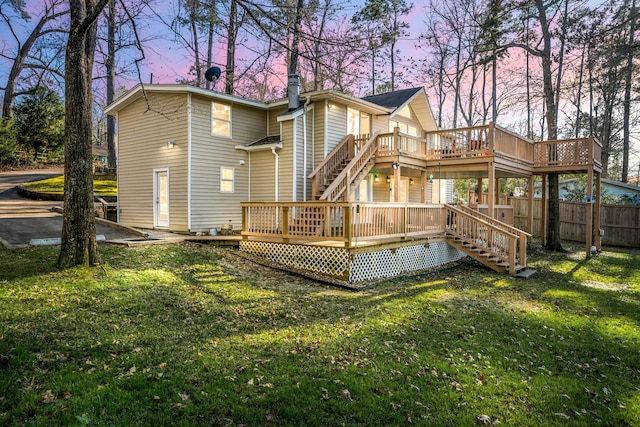 back of house with a chimney, fence, a deck, and a lawn