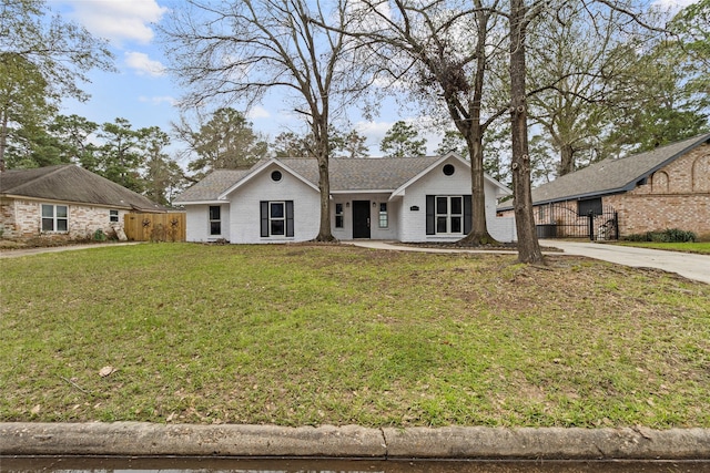 ranch-style house featuring concrete driveway, a front lawn, fence, and brick siding